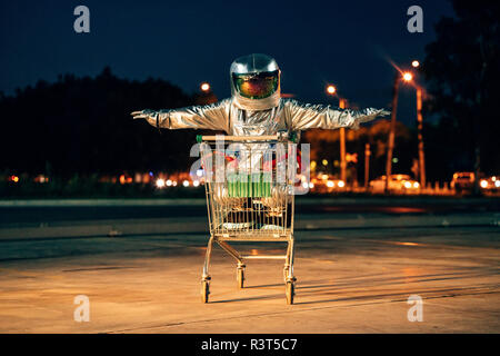 Spaceman in der Stadt in der Nacht auf Parkplatz innen Warenkorb Stockfoto