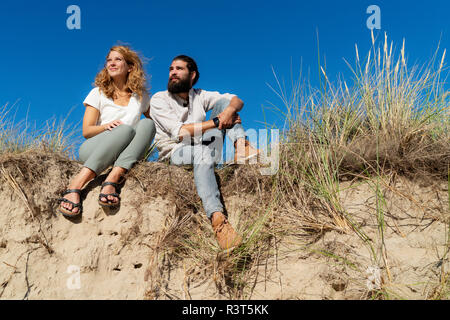 Junges Paar sitzt auf einer Düne im Sommer, entspannend Stockfoto