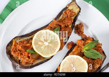 Ein türkisches Gericht von Imam bayildi, gebackenes Ei Anlage/Aubergine mit Lammhackfleisch und Tomaten Richtfest mit frischen Zitronenscheibe garnieren serviert. Stockfoto