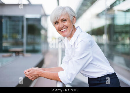 Portrait von gerne ältere Frau lehnte sich auf Geländer in der Stadt Stockfoto