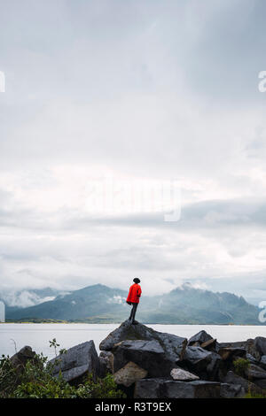 Norwegen, Insel Senja, Rückansicht der Mann, der auf einem Felsen an der Küste Stockfoto