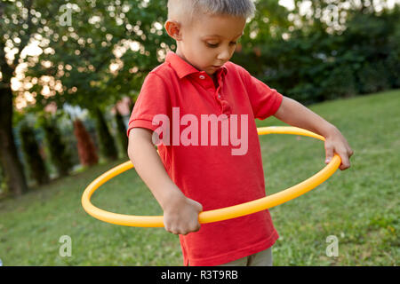 Junge spielt mit Hula Hoop in Garten Stockfoto