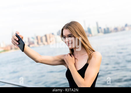 Junge Frau selfies nehmen am East River. Stockfoto