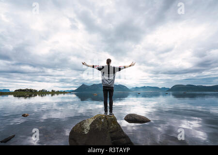 Norwegen, Insel Senja, Rückansicht der Mann, der auf einem Felsen an der Küste Stockfoto