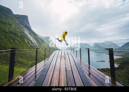 Norwegen, Insel Senja, Mann springen auf eine Aussichtsplattform an der Küste Stockfoto