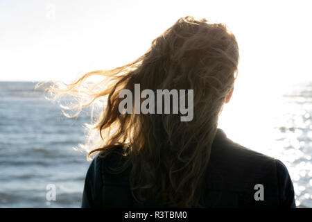 Blonde Frau mit Blick auf das Meer, Rückansicht Stockfoto