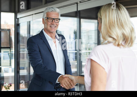 Geschäftsmann und Frau Händeschütteln im Büro Stockfoto