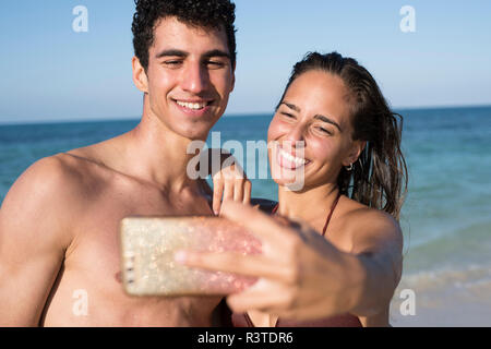 Glückliches junges Paar unter selfies am Strand Stockfoto