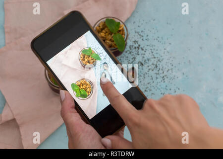 Woman's Hand unter Foto von Dessert mit Smartphone, close-up Stockfoto