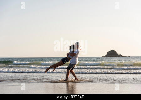 Junges Paar umarmt am Strand Stockfoto
