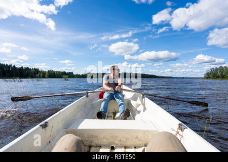 Finnland, Mann Rudern in einem Boot auf einem See Stockfoto