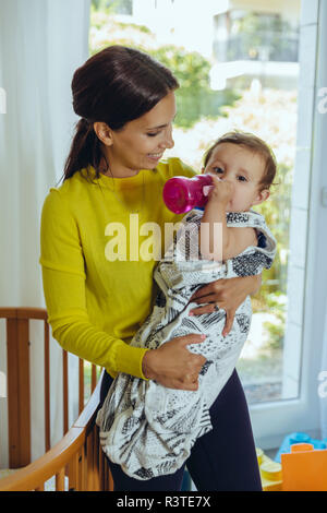 Lächelnde Mutter herauf ihr Baby Mädchen vom Bett Stockfoto