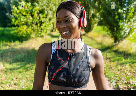 Junge Athlet in der Natur, Musik hören mit Kopfhörern Stockfoto