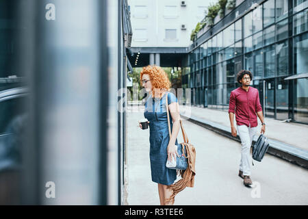 Junge Geschäftsfrau Window Shopping in der Stadt, die Durchführung von Kaffee Stockfoto
