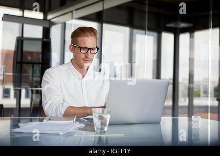 Geschäftsmann mit Laptop auf dem Schreibtisch im Büro Stockfoto