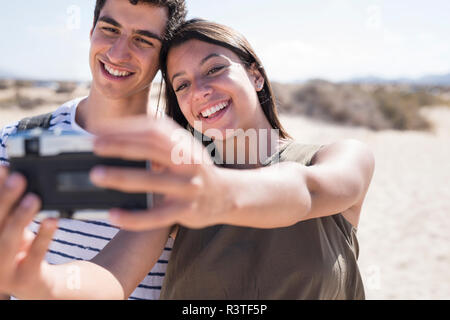 Ein junges Paar, das Spaß am Strand, wobei Smartphone selfies Stockfoto