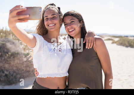 Freundinnen Spaß am Strand, wobei Smartphone selfies Stockfoto