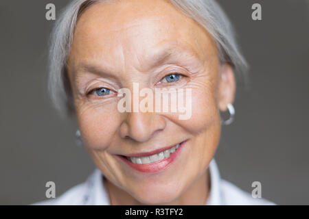 Portrait von lächelnden älteren Frau mit grauen Haaren und blauen Augen Stockfoto