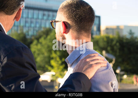 Ältere Unternehmer legen die Hand auf die Schulter des Jüngeren Geschäftsmann Stockfoto