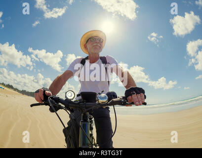 Frankreich, Bretagne, Sainte-Anne la Palud, Plage de Treguer, älterer Mann Riding Mountain e-Bike am Strand Stockfoto