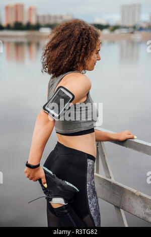 Junge athletische Frau stretching am Flußufer Stockfoto