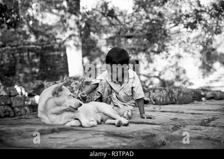 Siem Reap, Kambodscha - September 12, 2010: kambodschanischen Junge in der Nähe von einigen Ruinen spielt mit seinem Hund. Stockfoto