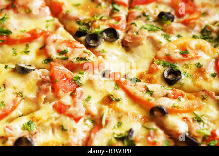 Heiße Pizza mit Käse, Schinken und Huhn, frische Tomatenscheiben und Oliven in Stücke geschnitten. Könnte als Lebensmittel Hintergrund oder im Restaurant Menü verwendet werden. Stockfoto