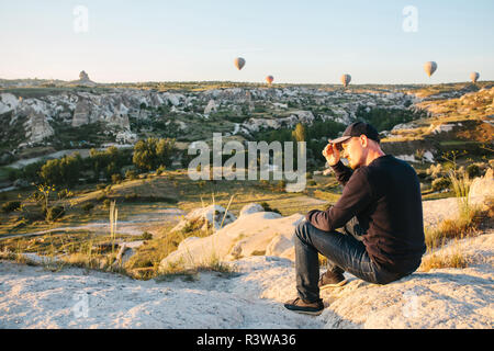 Ein Mann, der in der Einsamkeit bewundert einen schönen Blick auf das fliegende Ballons in Kappadokien in der Türkei. Stockfoto