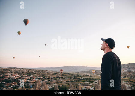 Ein Mann, der in der Einsamkeit bewundert einen schönen Blick auf das fliegende Ballons in Kappadokien in der Türkei. Stockfoto