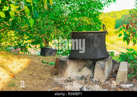 Alte Kupfer Topf zum Kochen stehen auf Beton Ziegel auf Kamin im Hinterhof Stockfoto