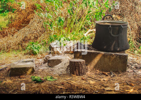 Alte Kupfer Topf zum Kochen stehen auf Beton Ziegel auf Kamin im Hinterhof der Farm Stockfoto