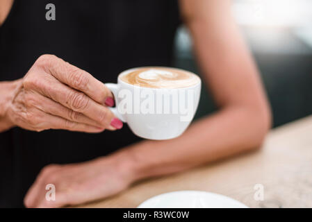 Nahaufnahme der älteren Frau mit einer Tasse Cappuccino Stockfoto