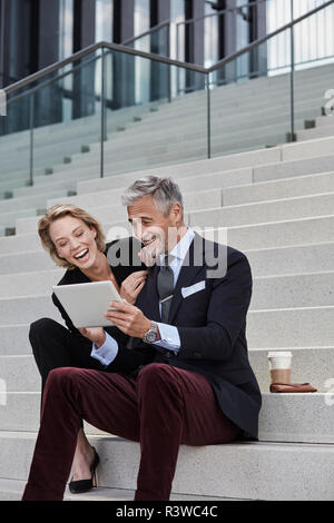 Porträt von zwei Geschäftsleute sitzen zusammen auf der Treppe am Tablet Spaß suchen Stockfoto