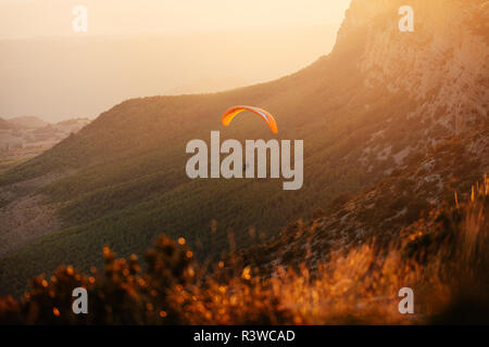 Spanien, Silhouette von Gleitschirm soaring hoch über die Berge bei Sonnenuntergang Stockfoto
