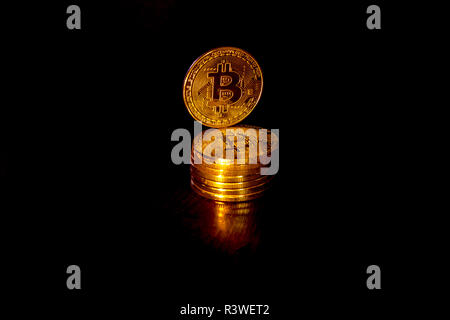 Crypto Währung bitcoin Goldmünzen auf schwarzem Hintergrund. Zusätzlich zu den liegenden Münzen, es gibt ständige Bitcoin. Stockfoto