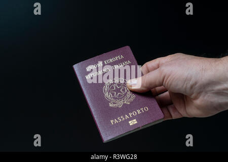 Der italienische Paß auf der Hand mit schwarzem Hintergrund. Stockfoto