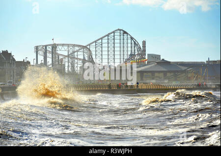 Menschen beobachten Wellen gegen Ufermauer mit der Pleasure Beach große Achterbahn im Hintergrund, Blackpool, Lancashire, Großbritannien Stockfoto