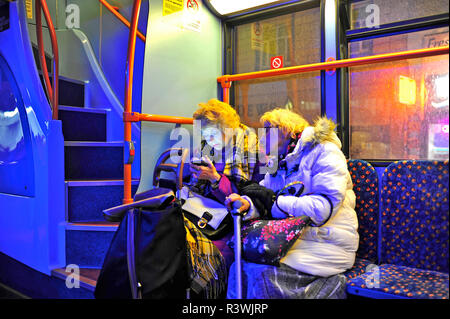 Zwei ältere Frauen sassen auf dem Bus in der Nacht zum Mobiltelefon suchen Stockfoto