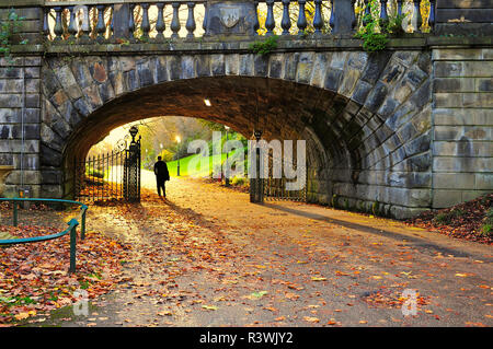 Silhouette der Menschen auf dem Weg durch Tore unter Brücke Trennung Avenham Park und Miller Park, bei Sonnenuntergang im Herbst Stockfoto