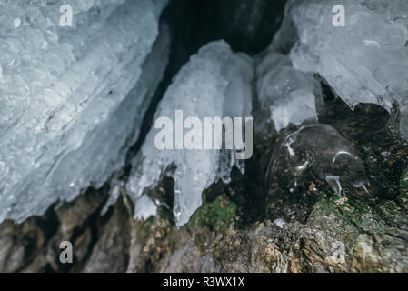 Winter Baikal. Insel Olchon. Eisgrotte. Dicke blaue Eis und Eiszapfen an der Küste Felsen der Insel Olchon im Winter. Natürliche Kälte Hintergrund. Der Gewinn Stockfoto