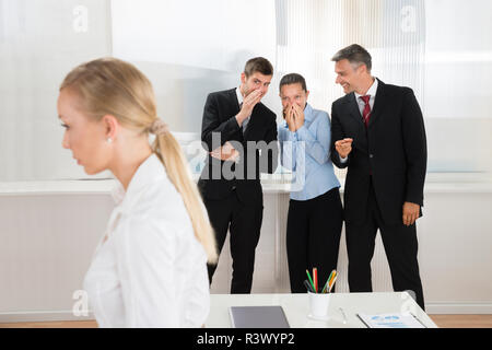 Geschäftsleute flüsternd über Frau Stockfoto