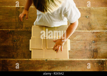 Die Hände der jungen Manipulation zählen Würfel auf Holz- Hintergrund in Montessori Classroom Stockfoto