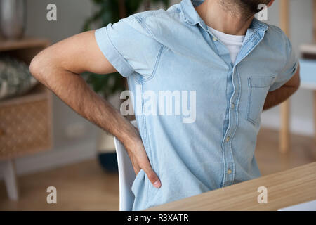 Verletzte männliche Ausdehnung in Stuhl Rückenschmerzen leiden. Stockfoto