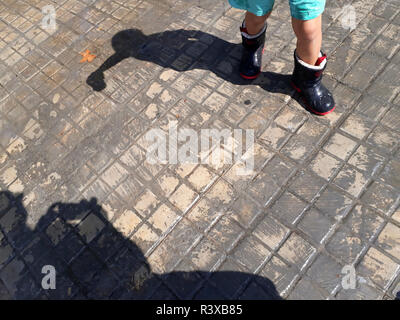 Glückliches Kind mit nassen regen Stiefel an einem verregneten Herbsttag. Stockfoto