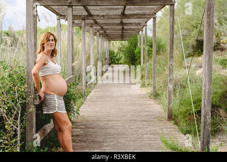 Schwangere Frau zu Fuß zwischen Bäumen und der Natur. Stockfoto