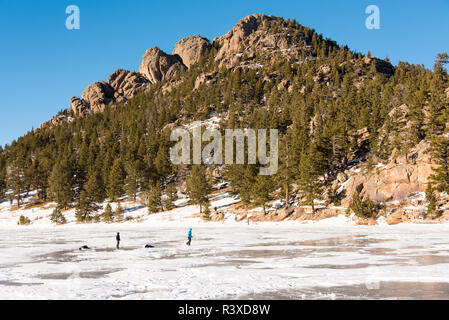 USA, Colorado, Estes Park. Gefrorene Lily See Teil der Rocky Mountain NP. Familie spielt auf Eis Stockfoto