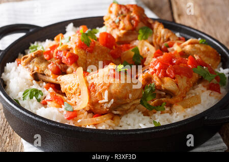 Haitianische Huhn Rezept ist ein Topf mit Hähnchenfleisch, Tomaten, Wein, Gewürze und Reis close-up auf den Tisch. Horizontale Stockfoto