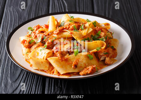 Italienische Nudeln mit langsamen gekochtes Schweinefleisch in einer würzigen Tomatensauce closeup auf einem Teller auf den Tisch. Horizontale Stockfoto