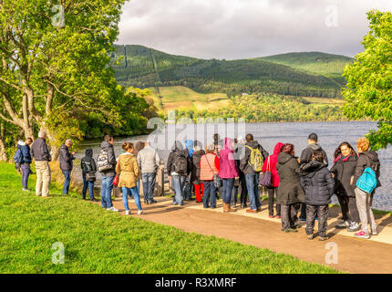 Eine Gruppe von Touristen für eine Bootsfahrt in der Nähe von Steg in Urquhart Castle Site sie an Bord für eine Rückreise auf See Loch Ness, Schottland zu nehmen warten Stockfoto