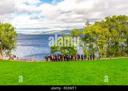 Einen malerischen Blick auf Loch Ness und Hochland mit einer Gruppe von Touristen stehen und warten auf die Rückkehr Boot, Schottland Stockfoto